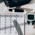 Close-up of a diabetes monitoring kit with glucometer, pen, and test strips on a table.